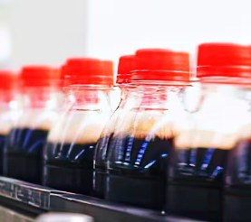 Dark sugary drinks in bottles moving along a production line